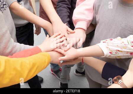 many different children's hands and the teacher's hand are held together while playing at school during recess Stock Photo