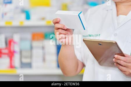 Pharmacist using computer tablet for search bar on display in pharmacy drugstore shelves background. Online medical concept Stock Photo