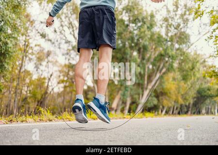 male feet jumping in mid air whilst using a Skipping Rope, jump rope in the park. Stock Photo
