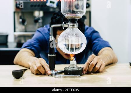 Professional coffee maker - Barista using coffee siphon brewing hot espresso at coffee shop Stock Photo