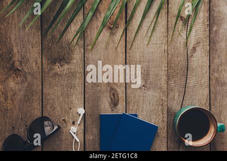 Flat lay travel concept, passports, cup of coffee, eyeglasses and earphones, palm leaf on wooden background. High quality photo Stock Photo