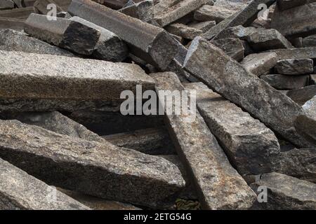Piled up, lying in disarray old rectangular cement grey road curbs piled up in connection with road maintenance, abstract rough background Stock Photo