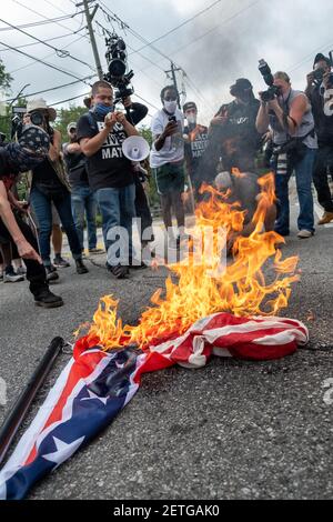 Stone Mountain, GA, USA. 15th Aug, 2020. Protesters burn an American flag and a Confederate flag during a 'Defend Stone Mountain' rally. Multiple right-wing militia groups and counter protesters were slated to converge in Stone Mountain, GA on Saturday. Stock Photo