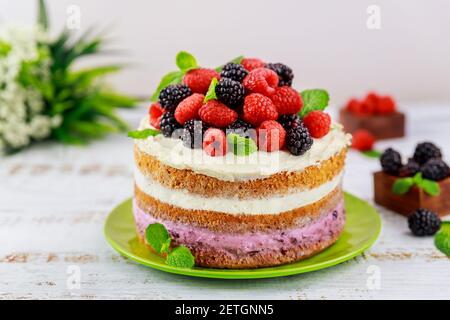 Homemade berry cake decorated with fresh raspberries and blackberries on white background. Stock Photo