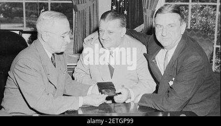Photograph of President Truman at his desk in the Oval Office, receiving his annual pass to National Football League... Stock Photo