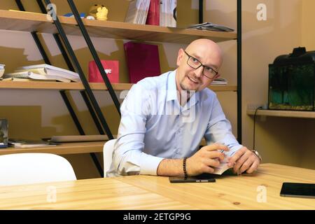 smiling bald businessman in eyeglasses read book and working in office. Stock Photo