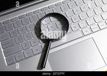 Magnifying glass on laptop computer keyboard. concept of search and web technology. Stock Photo