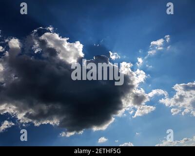 A ray of sun peeks through a dark cloud. Dark cloud in the sky. Sun from a cloud Stock Photo