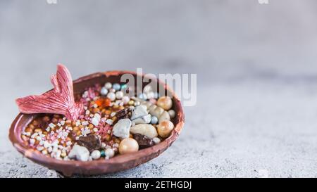 Half a chocolate egg filled with popped rice. The egg is decorated with multicolored precious stones and a mermaids tail Stock Photo