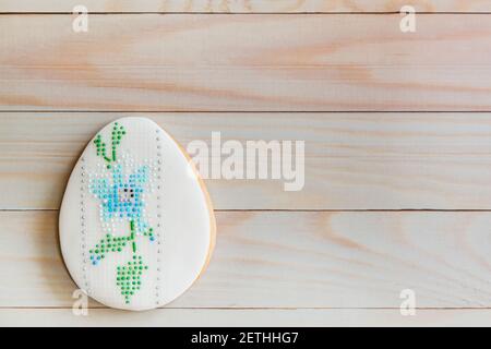 Hand painted gingerbread easter egg in the art diamond embroidery on wooden background. Easter greeting card concept. Top view. Flat lay. Copy space Stock Photo