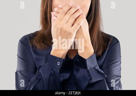 The woman in a dark blue shirt not commenting and refusing. woman with her hands on her mouth because of bad breath or halitosis Stock Photo