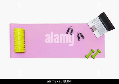 Fitness mat, dumbbells, expander and laptop for online workouts at home. Online education concept in relation to the pandemic. Isolated on white Stock Photo