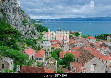 View of red roofs between mountain and sea in Omis city, Croatia, where the Cetina River meets the Adriatic Sea. View of small town situated between r Stock Photo