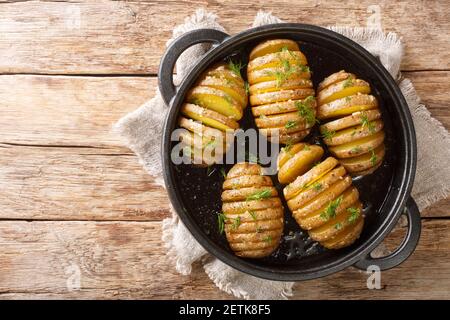 Swedish baked Hasselback potatoes close-up on a frying pan on the table. Horizontal top view from above Stock Photo