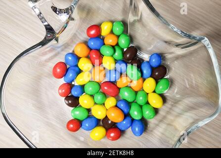 Multicolored chocolate-covered nuts in a transparent plate Stock Photo