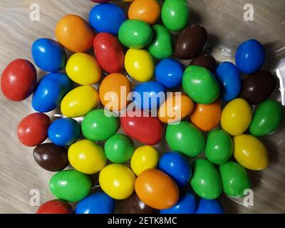 Multicolored chocolate-covered nuts in a transparent plate Stock Photo