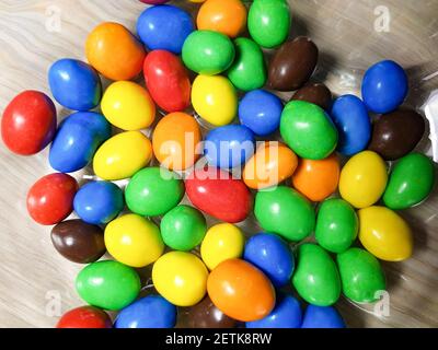 Multicolored chocolate-covered nuts in a transparent plate Stock Photo