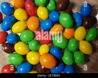 Multicolored chocolate-covered nuts in a transparent plate Stock Photo