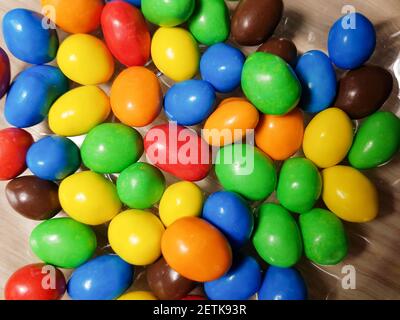 Multicolored chocolate-covered nuts in a transparent plate Stock Photo