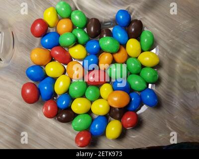 Multicolored chocolate-covered nuts in a transparent plate Stock Photo