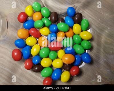 Multicolored chocolate-covered nuts in a transparent plate Stock Photo