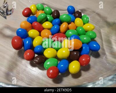 Multicolored chocolate-covered nuts in a transparent plate Stock Photo