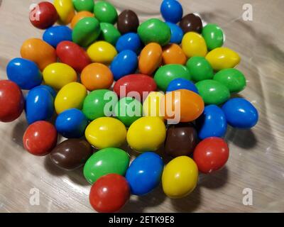 Multicolored chocolate-covered nuts in a transparent plate Stock Photo