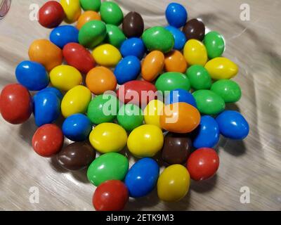 Multicolored chocolate-covered nuts in a transparent plate Stock Photo