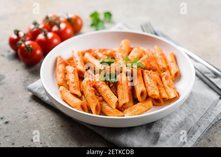 Penne pasta with tomato sause in white plate on stone background table. Closeup. Italian food. Stock Photo