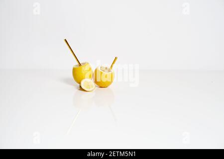 Lemonade concept. Yellow lemons and golden paper straws on white background Stock Photo