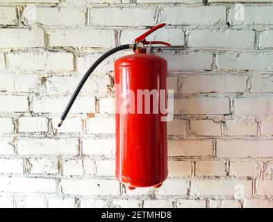 Powder fire extinguisher for extinguishing a fire close-up on a white brick isolated background Stock Photo