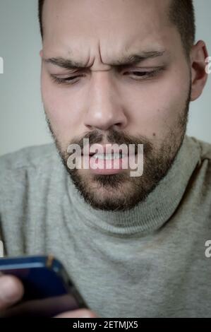Portrait of a worried young bearded man reading a message on his cellphone Stock Photo