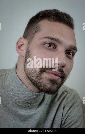 Portrait of a young brown-haired man with a short beard and a gray turtleneck sweater Stock Photo