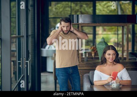 Woman with smartphone and man touching hands to head Stock Photo