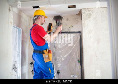 Skilled electrician using unimer for voltage checking Stock Photo