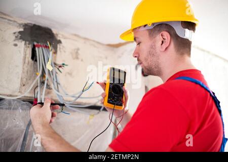 Electrician with unimer testing cable connectivity on a location of distribution board Stock Photo