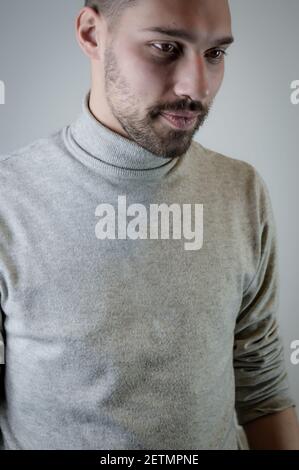 Portrait of a young brown-haired man with a short beard and a gray turtleneck sweater Stock Photo