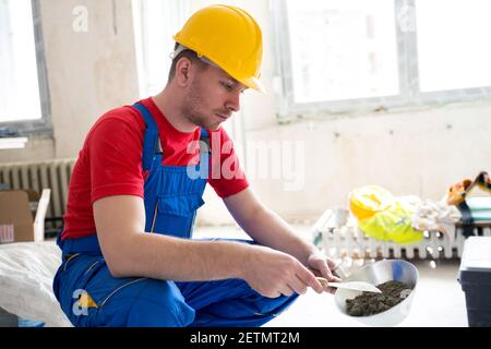 Manual making of gypsum mixture for filling of wall hollows Stock Photo