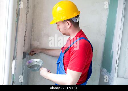Applying gypsum mixture on a wall hollows insuring cables stay fixed inside Stock Photo