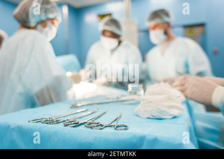 Tools for the operation in the foreground and a team of surgeons in the background performing the operation Stock Photo