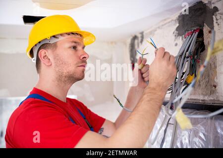 Electrician inspecting cables and wires in order to connect them on a distribution board Stock Photo