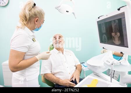 Dentistry concept. Professional dental services and modern equipment without pain. The doctor consults an elderly male patient and examines the teeth Stock Photo