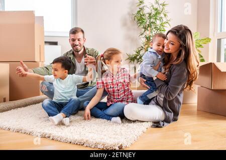 Freshly moved in family relaxing in new home while making a break Stock Photo
