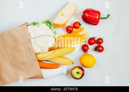 top view of paper bag with fruits, vegetables, spaghetti, cheese, milk on white background Stock Photo