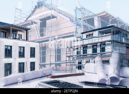 Three houses under construction with building plans in the foreground Stock Photo