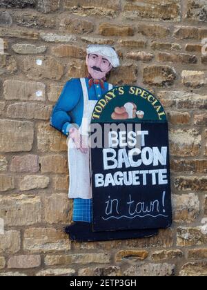 Colourful sign board outside a cafe offering The Best Bacon Baguette In Town; Olney, Buckinghamshire, UK Stock Photo