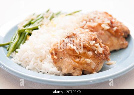 cripsy fried chicken thighs with vegetables over rice in a lemon sauce Stock Photo