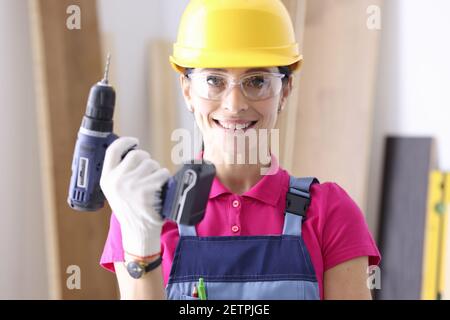 Woman builder in protective helmet holding drill in her hands Stock Photo