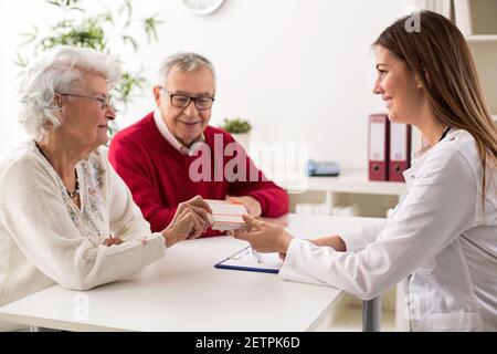Doctor giving drugs to her senior woman patient, closeup Stock Photo