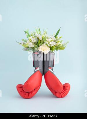 Spring flower bouquet in red boxing gloves on minimal blue